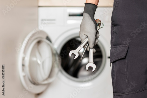 Repair Washing Machine. Washer Appliance Repair Service. Worker Hand with Tools Screwdriver and Wrench on Washing Machine Background. 