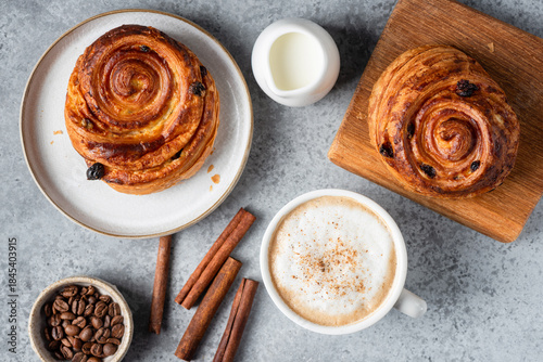 Konstfotografi Cappuccino coffee with cinnamon and cinnamon raisin swirl bun, baked puff pastry