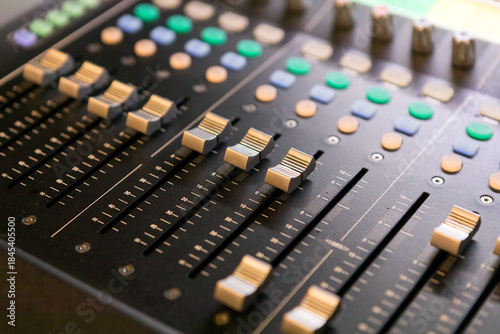 Close-up of an audio mixing console volume control panel.