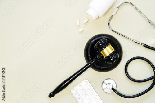 Foto Judge's gavel, stethoscope and pills  on a light green background