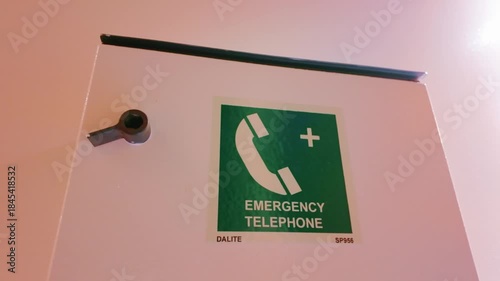 Emergency telephone sign on a cruise ship, featuring a green phone symbol and cross for quick access to safety services.