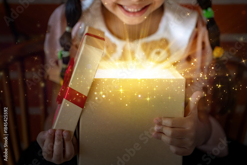 Smiling Child's Face While Opening a Magical Glowing Gift Box, Capturing Christmas Surprise and Joy