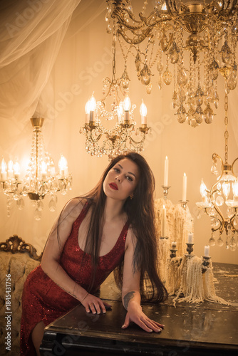 Passion brunette woman in shining red fashionable dress in vintage interior