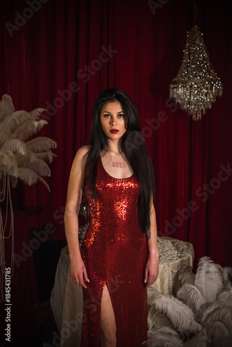 Passion brunette woman in shining red fashionable dress in vintage interior