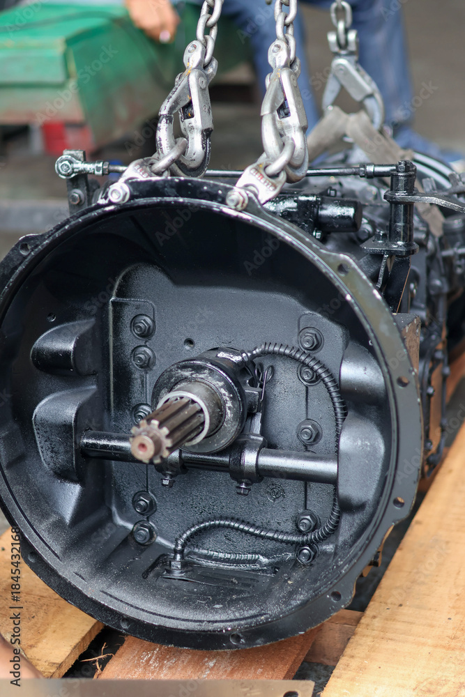 Fototapeta premium Heavy-duty truck or industrial gearbox being lifted by chains and shackles, showing the clutch housing and output shaft.