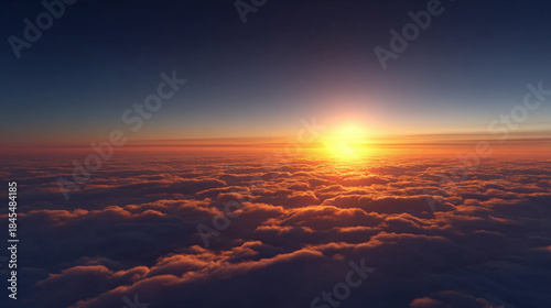 The sun setting over a sea of clouds, creating a stunning visual display of natural beauty. The sky is awash with warm hues of orange and yellow, and the clouds appear soft and fluffy.