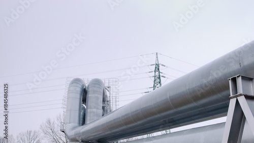pipeline and power transmission tower against gray sky