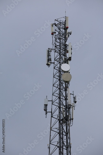 Wireless communication technology uses a steel tower with a cell phone antenna for radio signal transmission to the mobile network in the blue sky