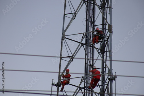 High voltage transmission towers carry electric power cables across the blue sky, supplying energy to industry