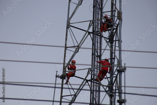High voltage transmission towers carry electric power cables across the blue sky, supplying energy to industry