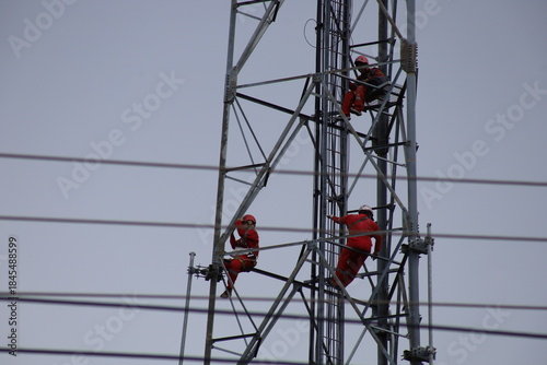 High voltage transmission towers carry electric power cables across the blue sky, supplying energy to industry