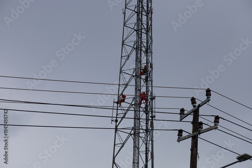 High voltage transmission towers carry electric power cables across the blue sky, supplying energy to industry