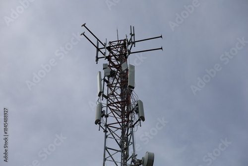 Tower crane and communication antenna on a steel structure construction site against a blue sky, representing wireless telecommunication network technology and the building industry