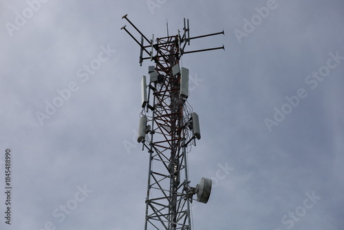 Tower crane and communication antenna on a steel structure construction site against a blue sky, representing wireless telecommunication network technology and the building industry