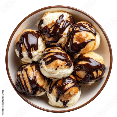 Indulgent top view of sweet cream puff dessert in bowl, with delicious chocolate sauce drizzle over each pastry