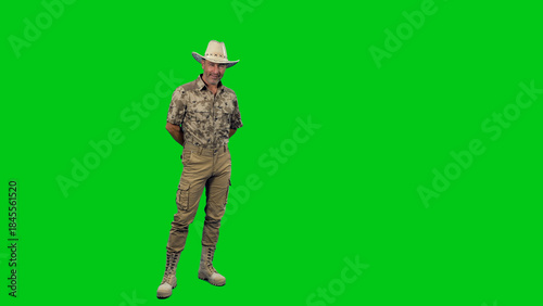 American middle aged man ranger wearing camouflage with cowboy hat and boots standing and looking at camera against green screen