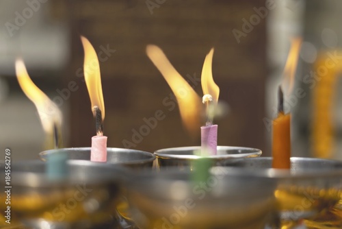 Oil lamps lit by believers as a symbol of the light of wisdom (the light dispels darkness and ignorance) in front of a Buddha statue, Wat Yannawa in the Sathon district, Bangkok, Thailand