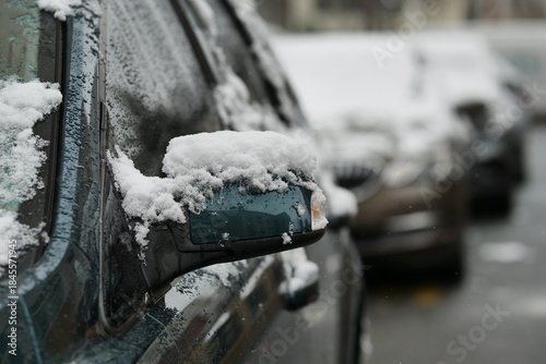 A close-up shot of a car heavily covered in fresh, wet snow on a winter day.
