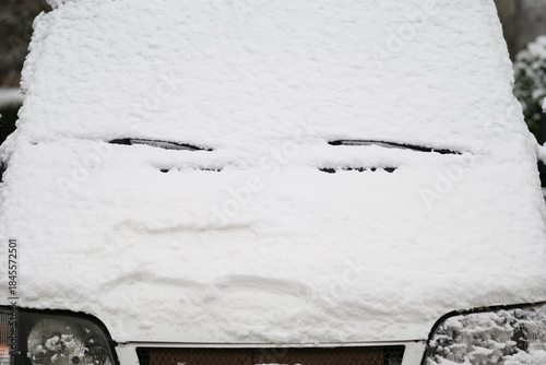 A close-up shot of a car heavily covered in fresh, wet snow on a winter day.