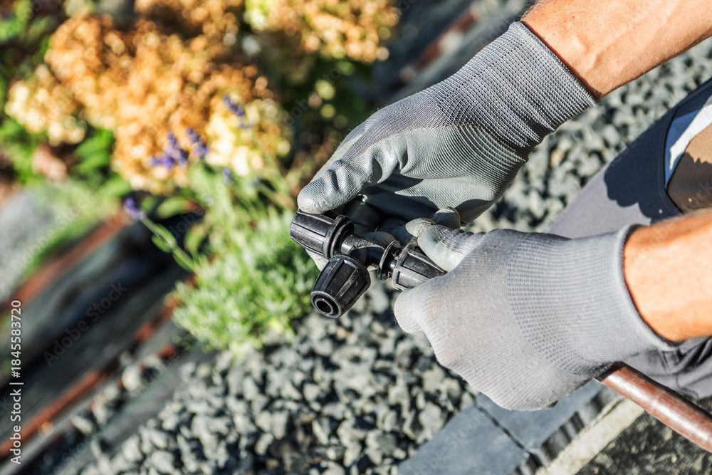 Fototapeta premium Gardener Works With Irrigation Tool Near Flowers
