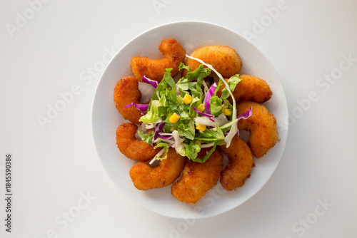 Gamberi impanati fritti e insalata mista su piatto bianco