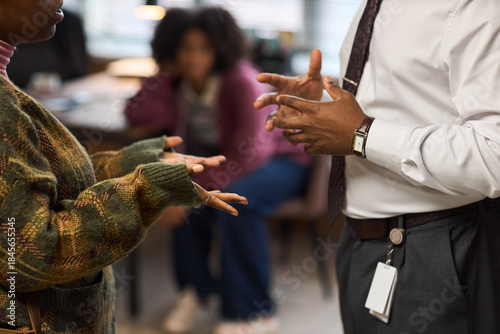 Obraz na płótnie Middle aged Black man gesturing with hands while talking to young adult Black wo