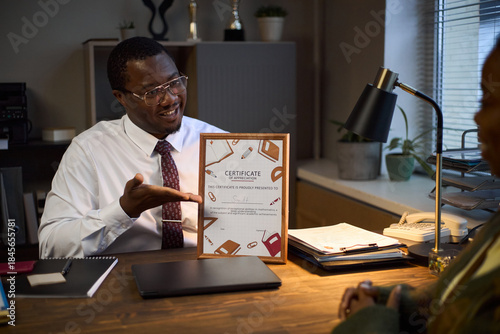 Εκτύπωση καμβά Middle aged Black man wearing glasses sitting at desk smiling and presenting cer