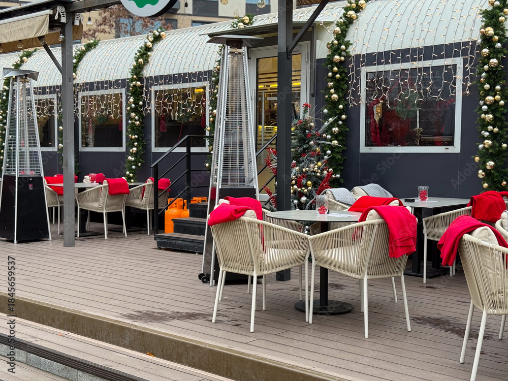 Obraz premium Christmas decorated cafe with heaters and garlands. Winter dining area, festive exterior and seasonal urban hospitality