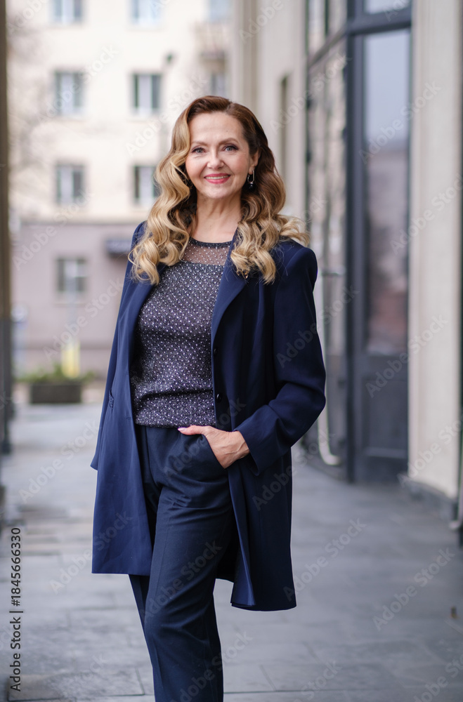 Fototapeta premium Confident middle aged business woman, confident lady manager, mature female professional executive, corporate leader wearing suit standing in office arms crossed looking at camera. Vertical portrait.