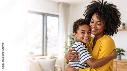 Happy African American mother hugging her smiling son at home. Loving black family showing affection and bonding. Motherhood concept with copy space
