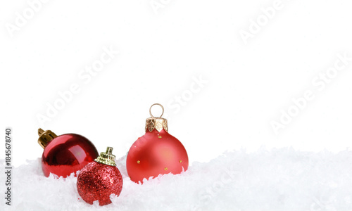 PNG image of Three vibrant red christmas ornaments resting in soft white snow against a dark night sky with falling snowflakes background on transparent background