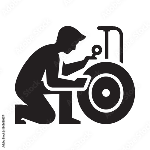 Silhouette of a person repairing a tire on a vehicle