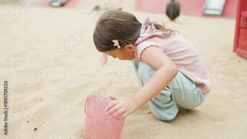 A girl plays in a sandbox on a playground in a park