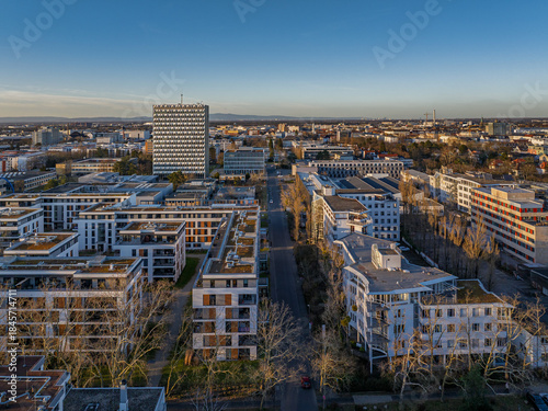 Aerial view of modern buildings and tree-lined streets under a clear sky, contrasting with the distant skyline, Darmstadt, Hessen, Germany.