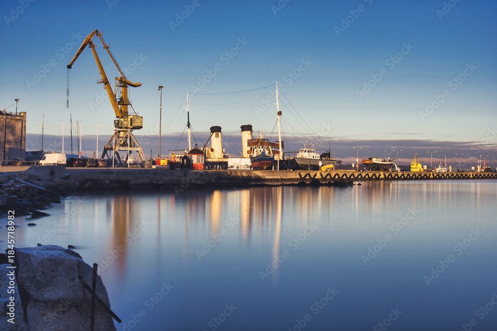 Fototapeta premium Historic Ships and Crane at Tallinn Seaplane Harbour at Sunrise