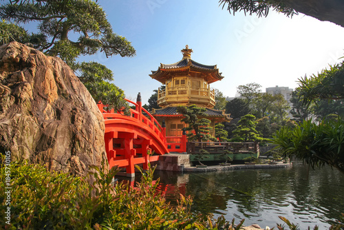 The Golden pavilion and red bridge at sunrise, in Nan Lian Garden near Chi Lin Nunnery, famous landmarks in Hong Kong .