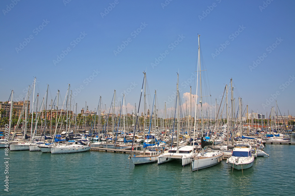 Fototapeta premium View from Rambla De Mar of the marina & many yacths moored at Port Vell which is a waterfront harbor and part of the Port of Barcelona, Catalonia, Spain.