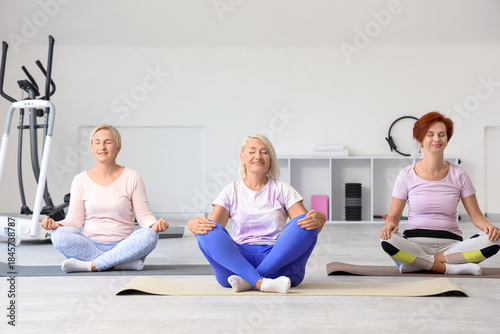 Sporty mature women meditat...