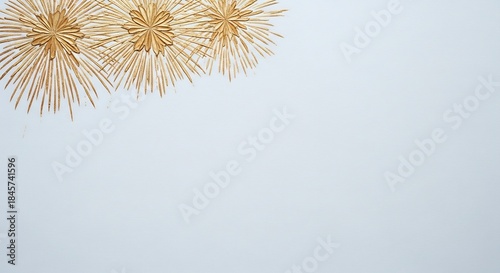 Three golden starbursts made of straw on a light blue background.