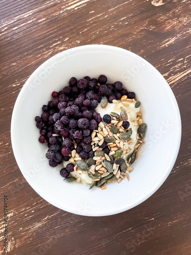 Cottage cheese mixed with yogurt topped with frozen blueberries and seed mix served as breakfast or snack. Simple nutritious meal focused on protein fiber and natural ingredients