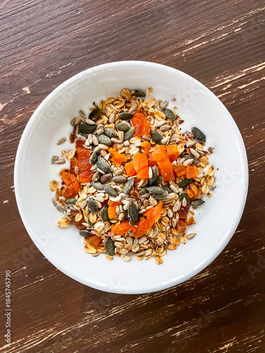 Yogurt served in bowl with toasted oats, mixed seeds and dried fruits for breakfast. Simple balanced meal prepared at home and ready to eat