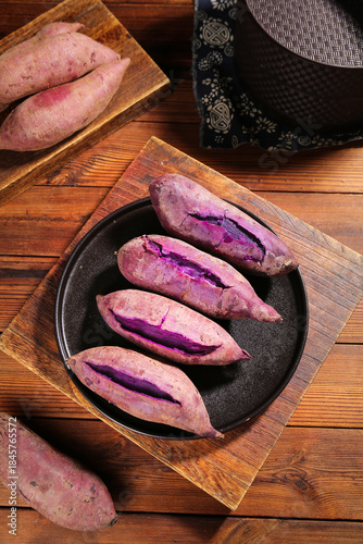 Fresh Purple Sweet Potatoes in Cast Iron Pan on Wooden Table
