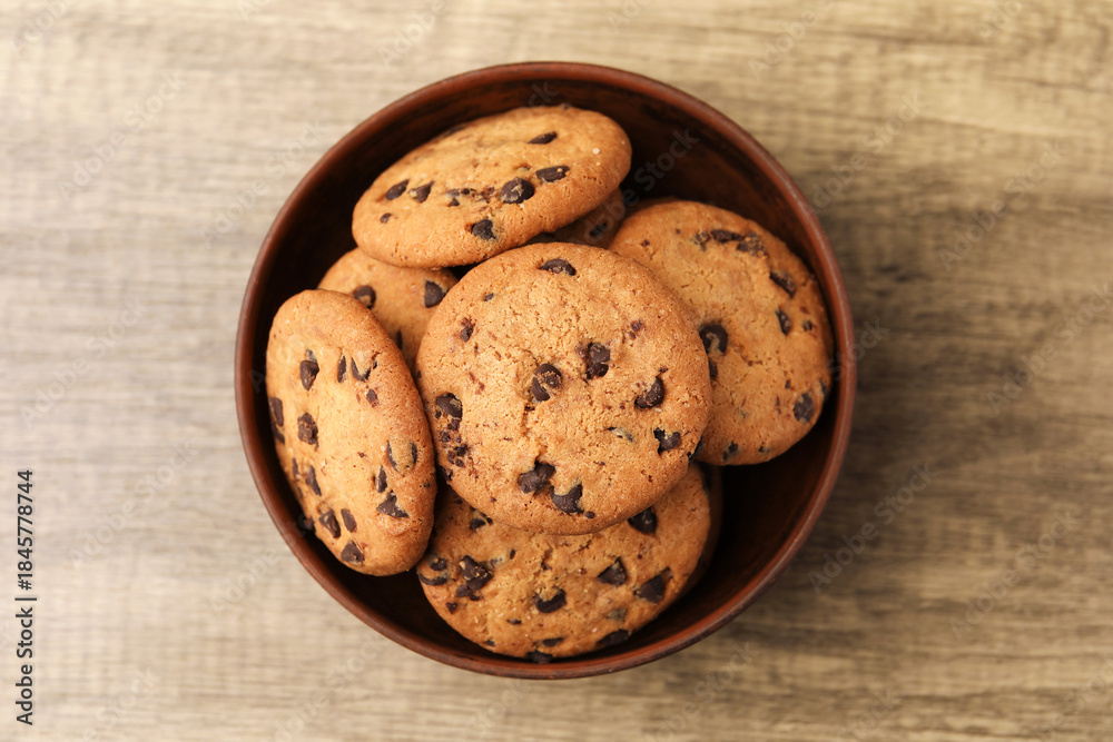 Obraz premium Delicious chocolate chip cookies in bowl on wooden table, top view