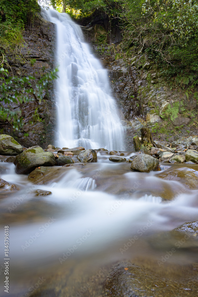 Obraz premium Stunning mountain waterfall captured with long exposure, creating smooth flowing water and highlighting natural textures, rocks, and surrounding greenery. Perfect for nature, landscape, or travel proj