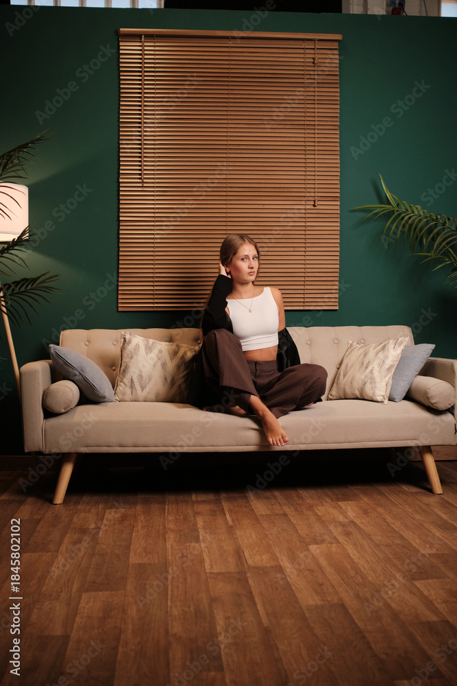 Obraz premium Young woman relaxing on sofa in modern living room