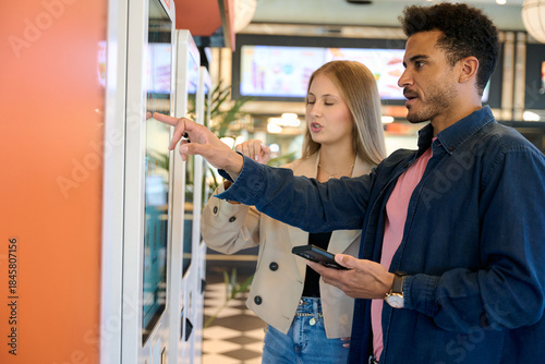 Bilde på lerret Couple ordering food at self service kiosk in fast food restaurant