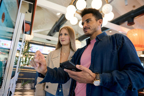 Couple ordering food at self service restaurant kiosk