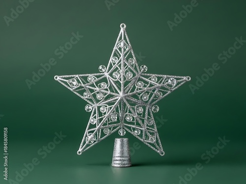 Shimmering silver christmas star tree topper adorned with clear gems against a rich green backdrop