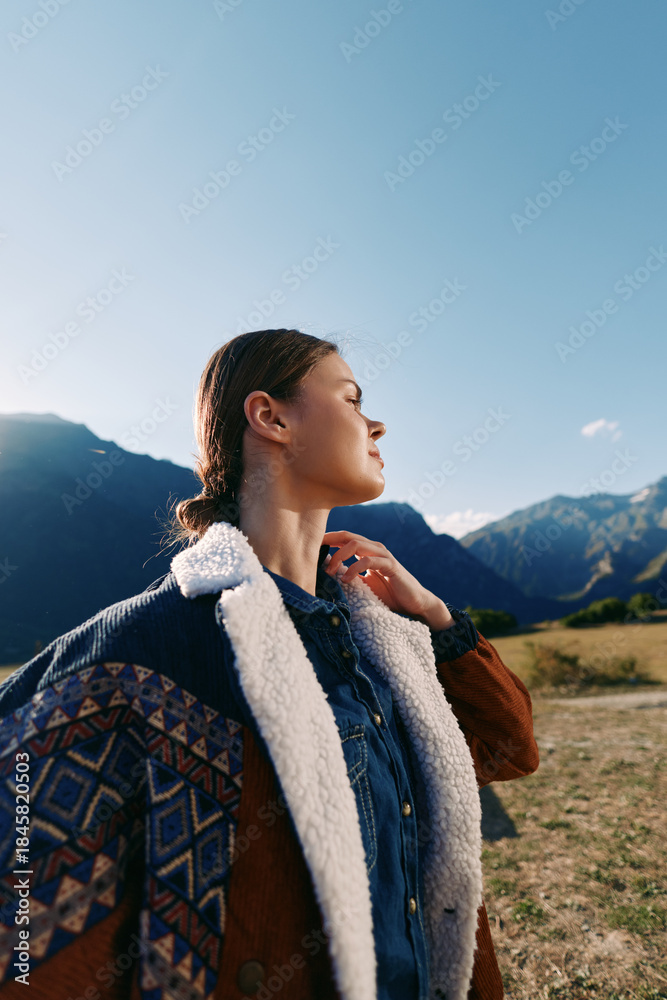 Fototapeta premium Woman portrait in the mountains hiking outdoors with backpack and jacket, enjoying sunlight and nature, travel adventure and serene landscape for leisure and exploration moments.