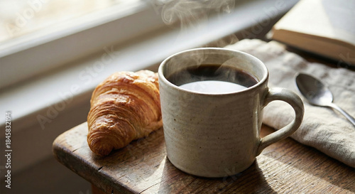 Steaming coffee mug with croissant on rustic wooden table
